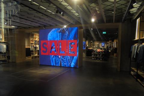 Rather than just showing a digital Sale sign in red, the screen alternates Sale banners, one of which is backed by blue denim
